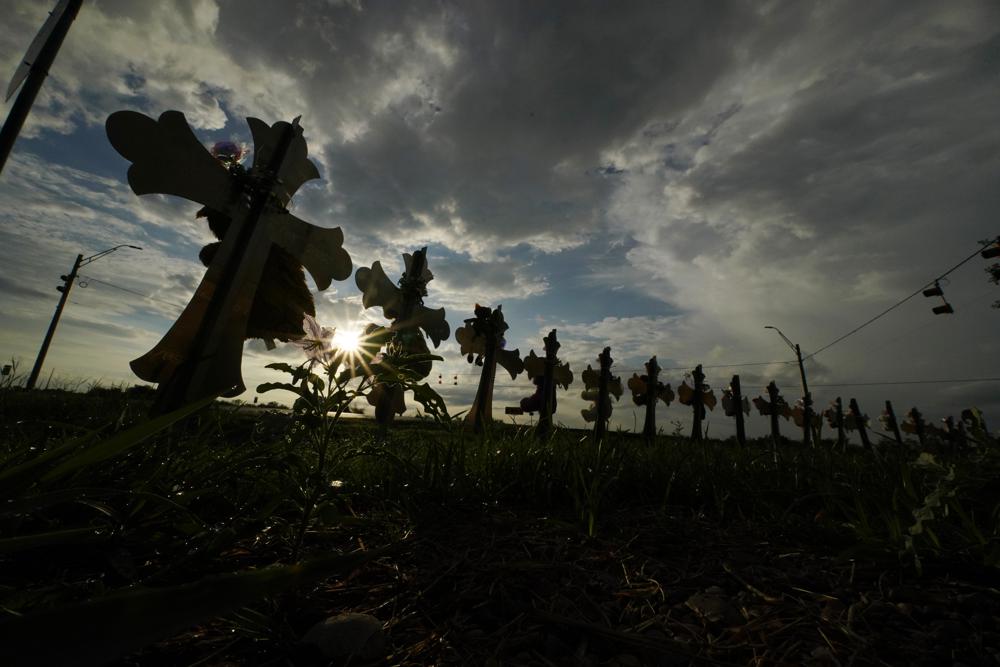 Vehicles pass crosses placed to honor the victims of the shootings at Robb Elementary School,(AP Photo/Eric Gay, File)