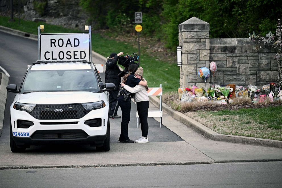 A woman hugs a police officer at the entrance of the Covenant School at the Covenant Presbyterian Church, in Nashville, March 28, 2023.