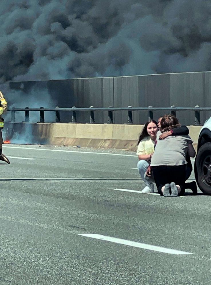 This photo provided by Angelique Feliciano shows people embracing as firefighters and police respond after a crash