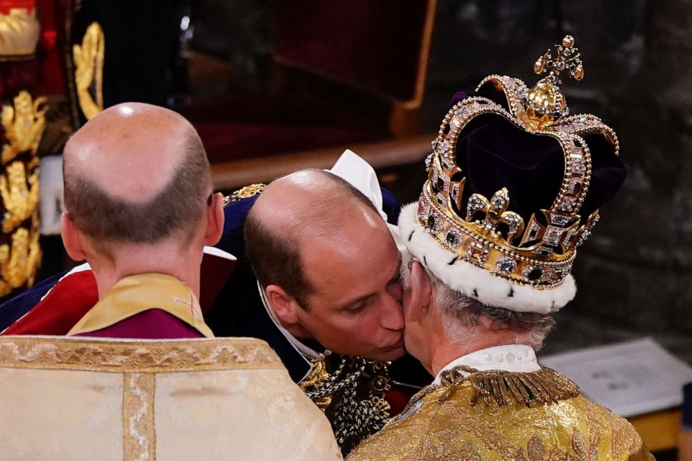 Prince William, Prince of Wales kisses his father, King Charles III, wearing the St Edward's Crown, during the King's coronation ceremony at Westminster Abbey, May 6, 2023, in London.