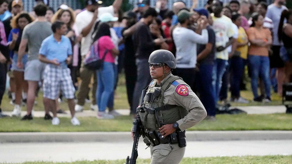A law enforcement officer walks as people are evacuated from a shopping center where a shooting occurred, May 6, 2023, in Allen, Texas.