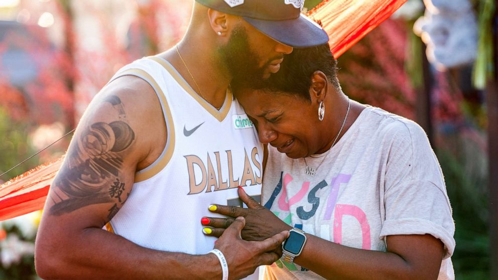 Robert Jackson consoles Cheryl Jackson at a makeshift memorial outside the Allen Premium Outlets, May 8, 2023, in Allen, Texas.