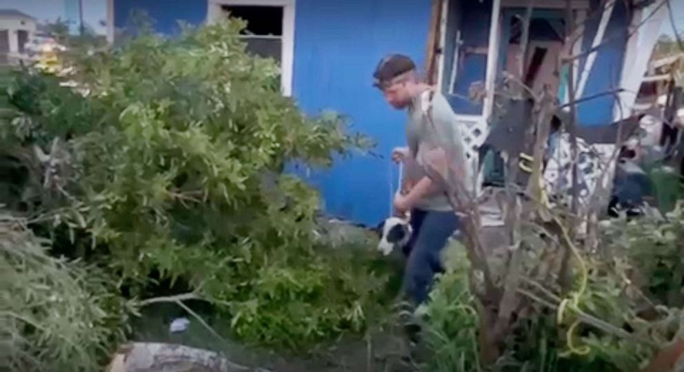 ABC News sound technician Jim Gower leads this dog out of harm's way after rescuing the animal from under a damaged home on May 14, 2023, following an apparent tornado touched down in Laguna Heights, Texas.