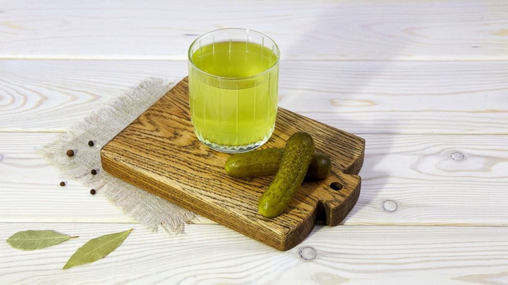 In an undated stock photo, pickle juice is seen in a glass next to two pickles. (Getty Images)