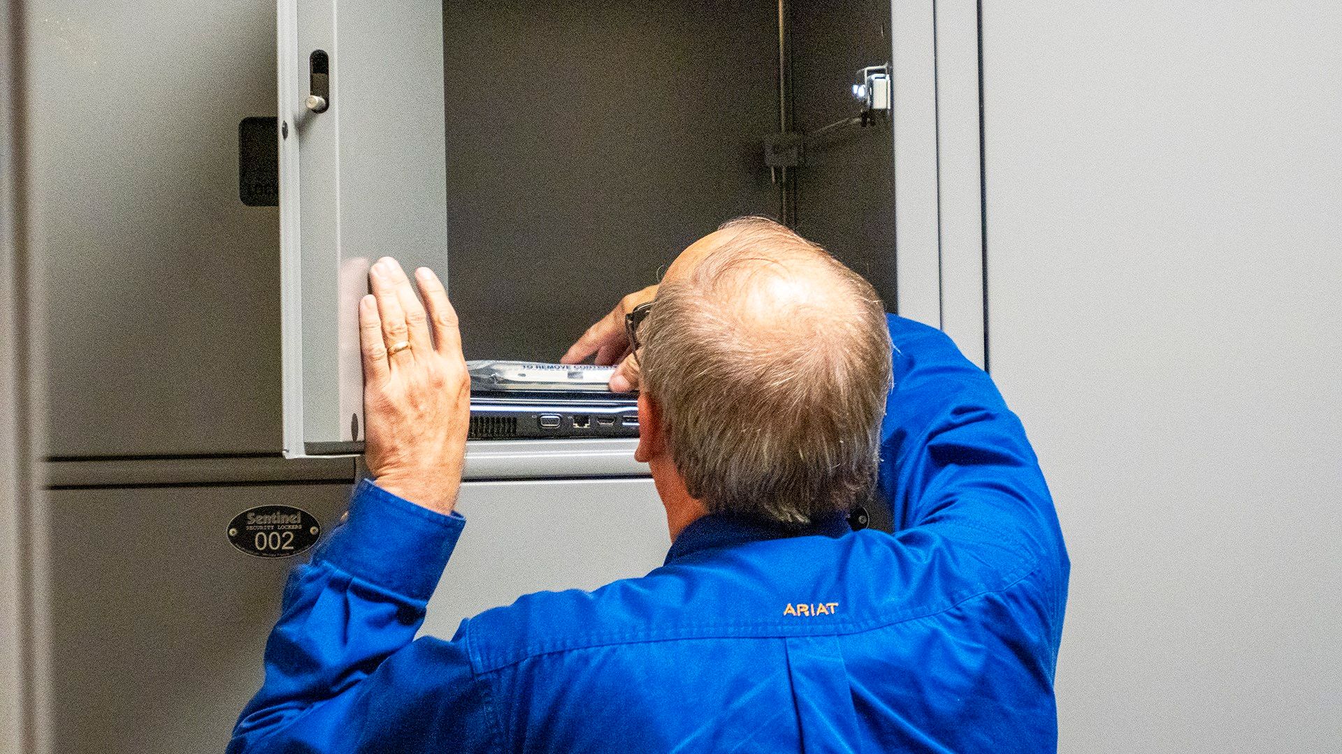 A Marion County undersheriff on Aug. 16, 2023, reaches into an evidence locker for items seized from the Marion County Record during an Aug. 11, 2023, raid. (Sherman Smith/Kansas Reflector)