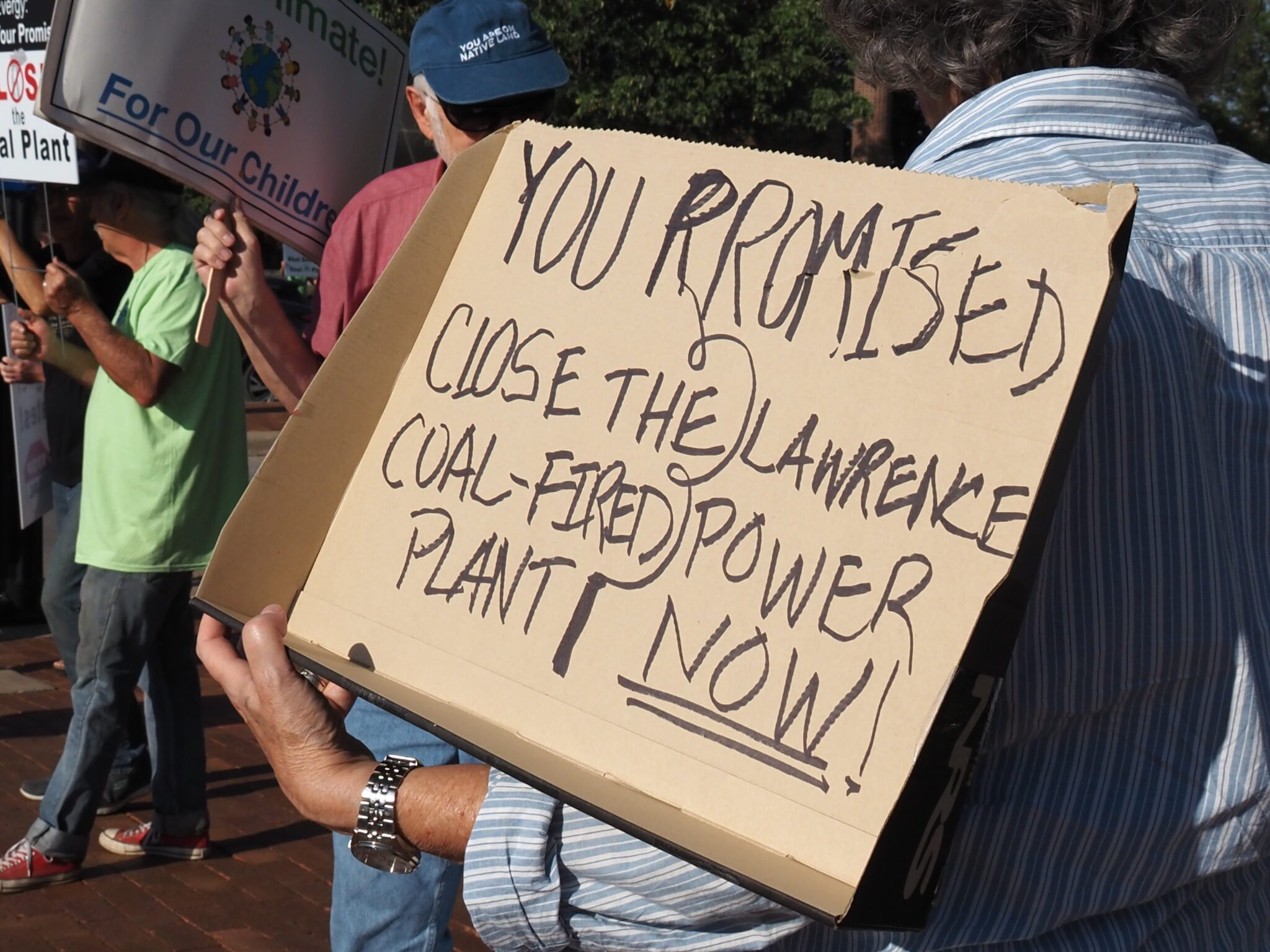 Demonstrators hold signs in support of closing the Lawrence coal-fired power plant during a Sept. 13, 2023, rally. (Rachel Mipro/Kansas Reflector)