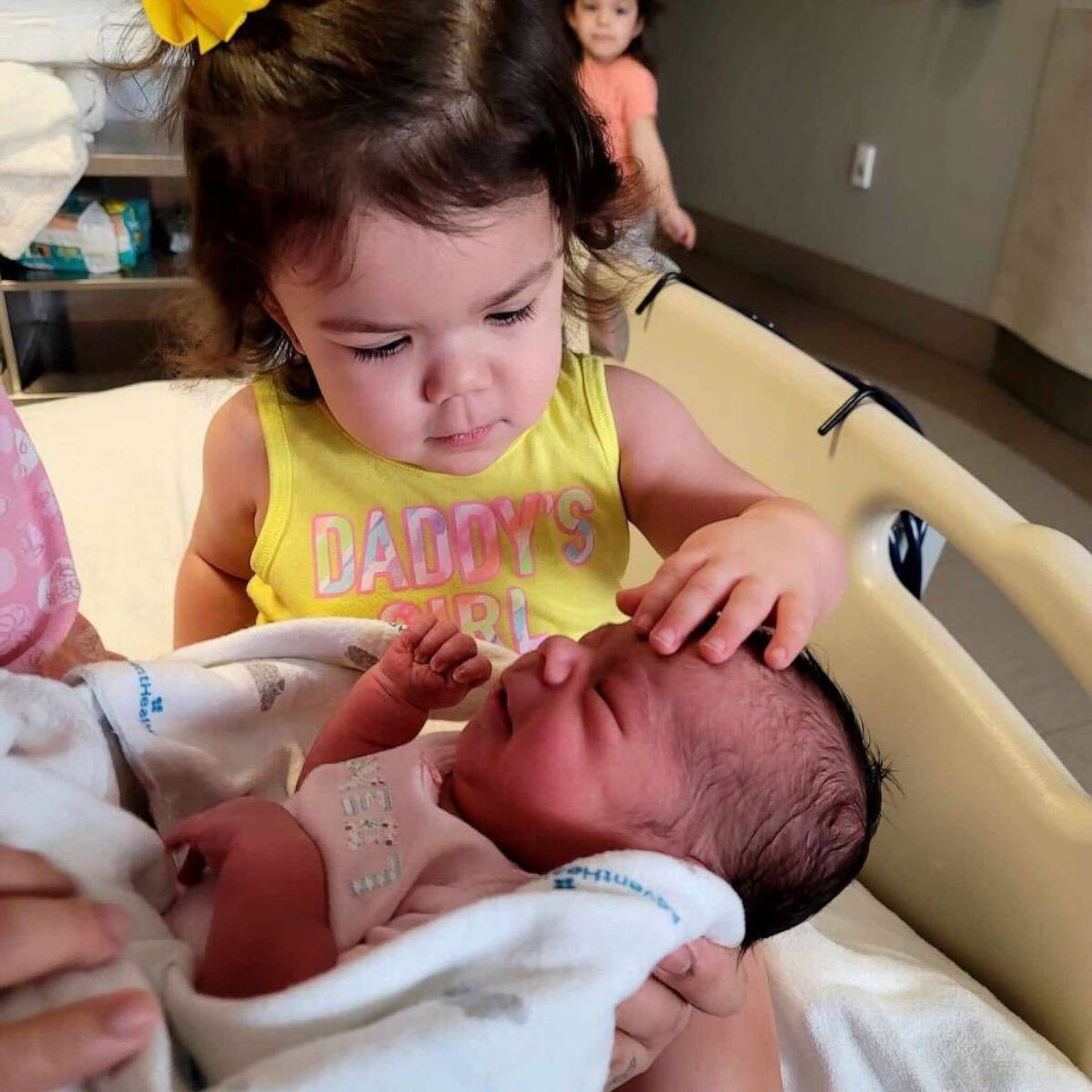 Jessica, 2, meets newborn Juliet, her new sister, born on the same day.